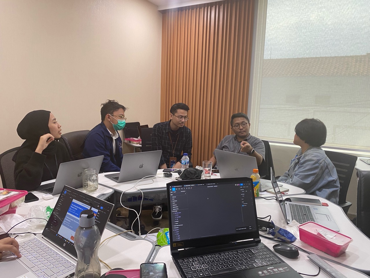 Product designers in a BRIdex workshop discussing design-system work around a table.