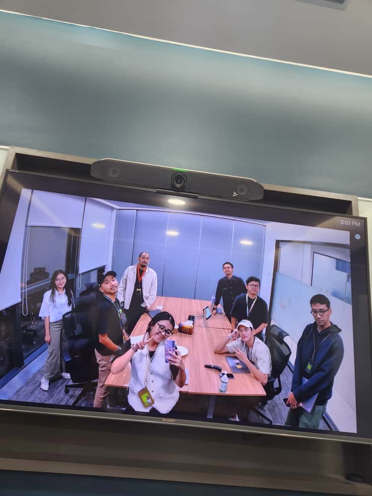 Colleagues together on a video call in a meeting room.