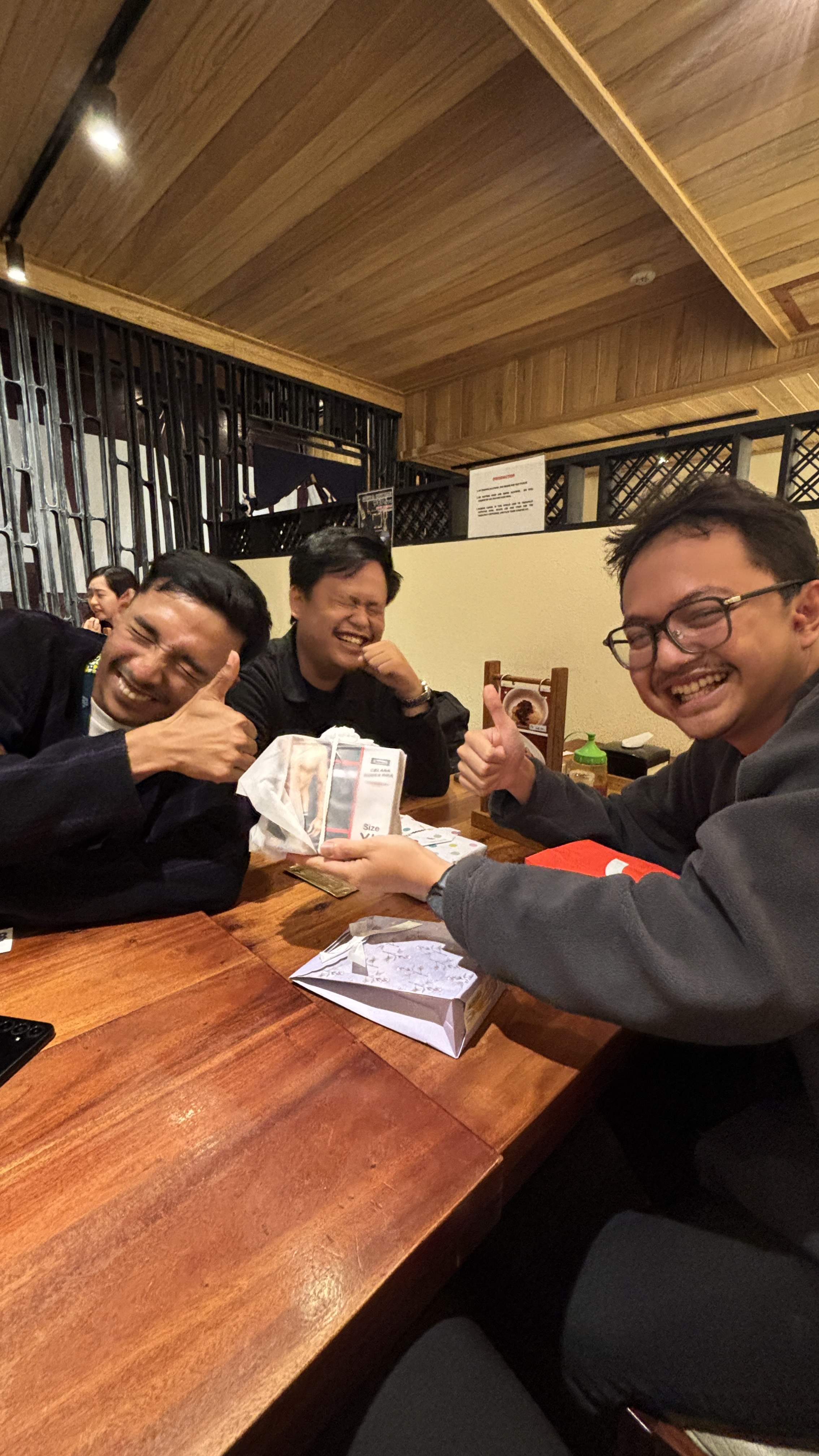 Colleagues smiling together around a table over dinner.
